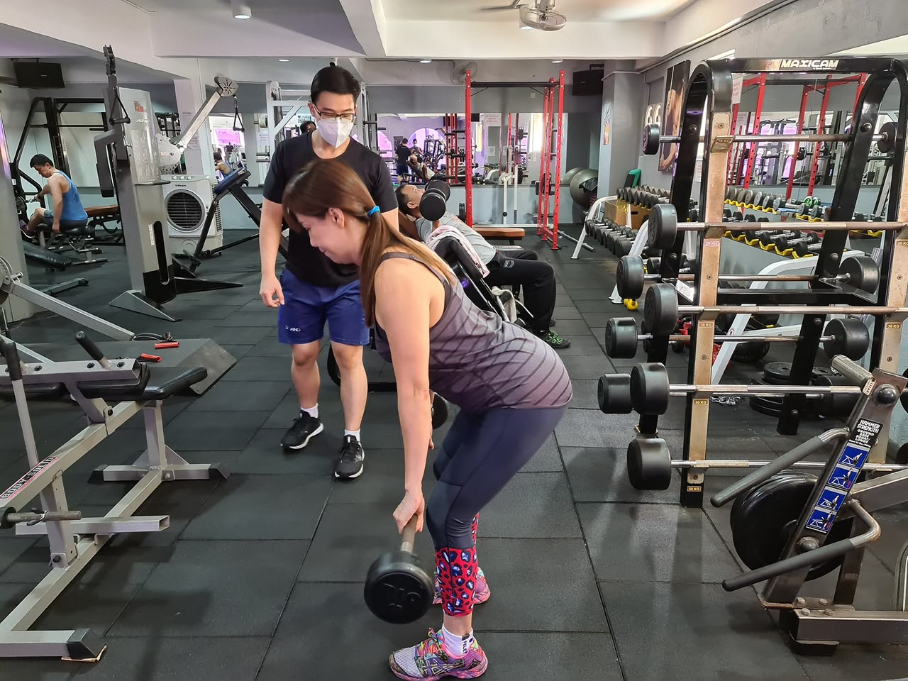 Personal trainer coaching a client on dumbbell rows at Amazonian Fitness